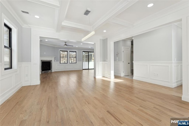 unfurnished living room with beam ceiling, ornamental molding, ceiling fan, and light wood-type flooring