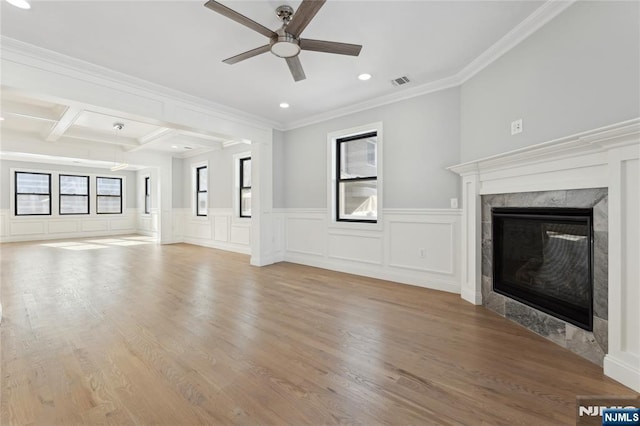 unfurnished living room featuring crown molding, light hardwood / wood-style flooring, beamed ceiling, ceiling fan, and a tiled fireplace