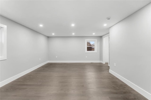 empty room featuring baseboards, dark wood-type flooring, and recessed lighting