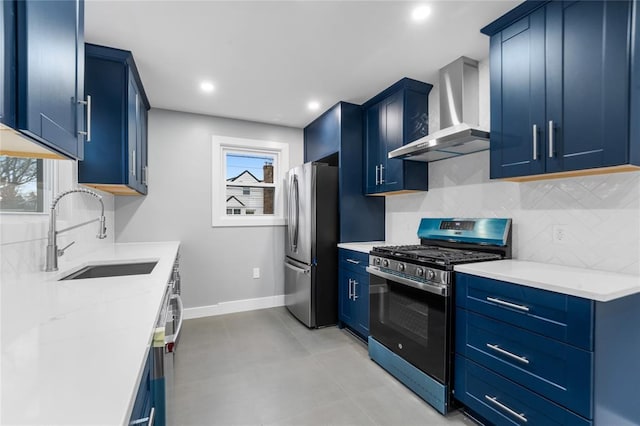 kitchen with wall chimney exhaust hood, appliances with stainless steel finishes, a sink, and blue cabinets