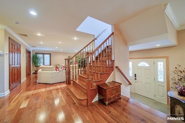 foyer with a skylight, crown molding, and light hardwood / wood-style flooring