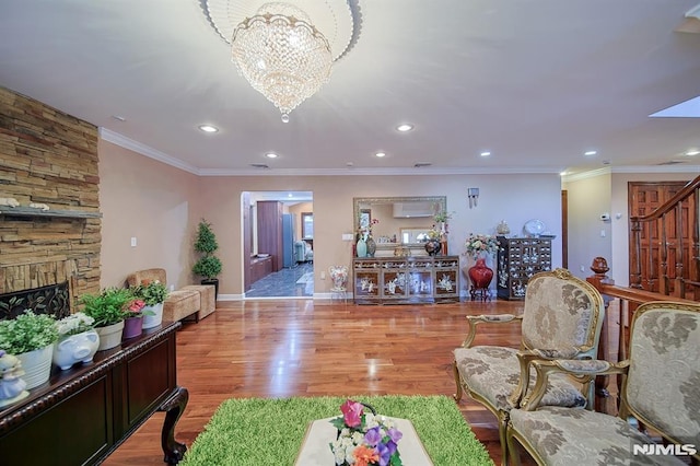 living room featuring light hardwood / wood-style floors, a stone fireplace, crown molding, and a chandelier