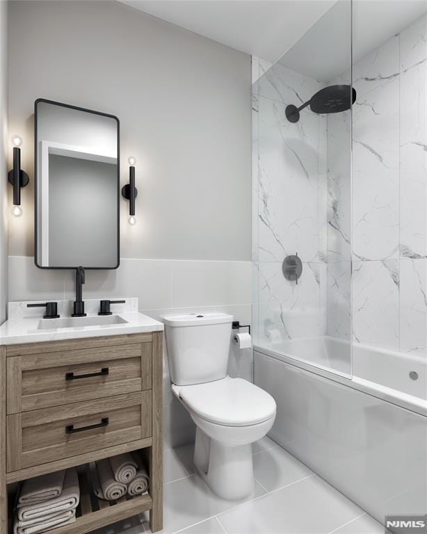 full bathroom featuring tile patterned floors, vanity, tiled shower / bath combo, tile walls, and toilet