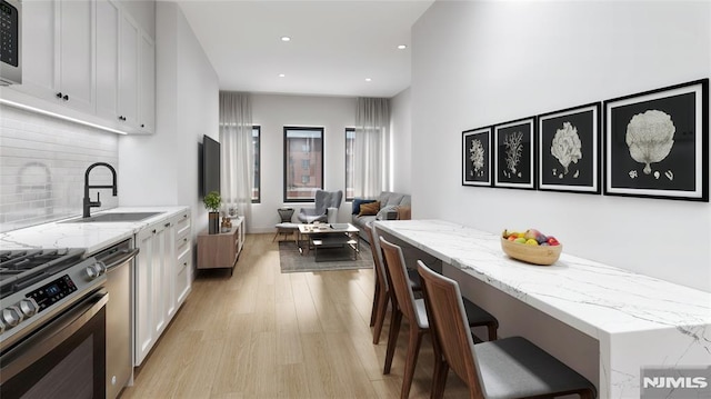 kitchen with light stone countertops, a kitchen bar, white cabinetry, and backsplash