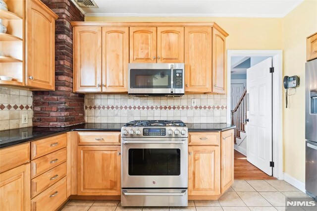 kitchen featuring backsplash, light tile patterned floors, and appliances with stainless steel finishes