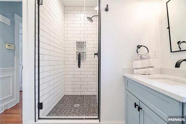 bathroom with vanity, wood-type flooring, and a shower with shower door