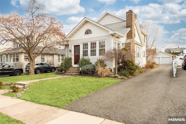 view of front of house featuring a garage, an outdoor structure, and a front yard