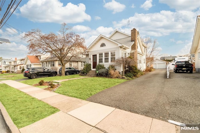 view of front of property with an outbuilding, a garage, and a front lawn