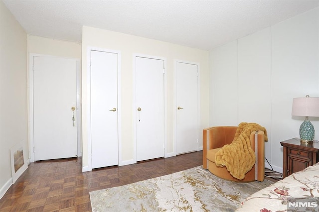 bedroom featuring a textured ceiling, dark parquet floors, and two closets