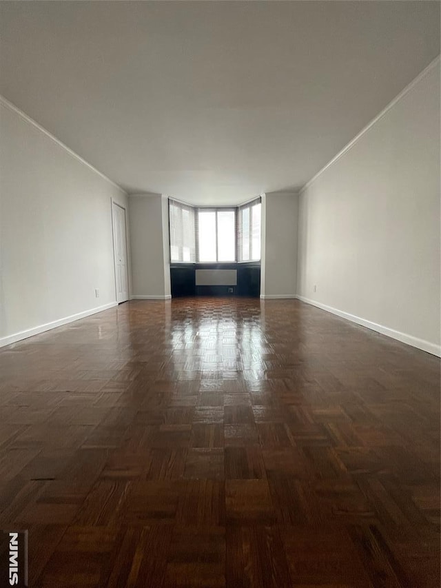 unfurnished room featuring dark parquet flooring and ornamental molding