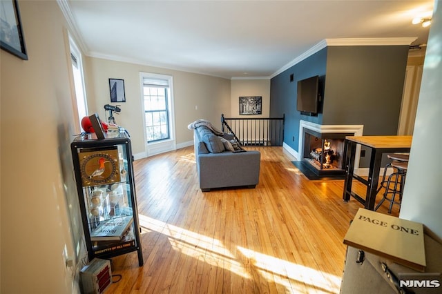 living room featuring a multi sided fireplace, crown molding, and light wood-type flooring