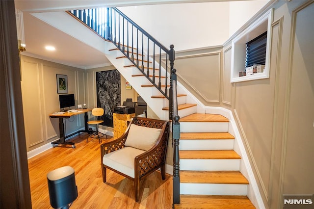 stairs with wood-type flooring and ornamental molding