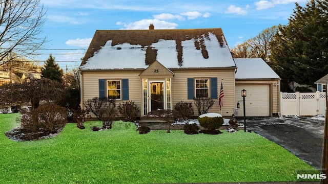 cape cod house featuring a front yard and a garage