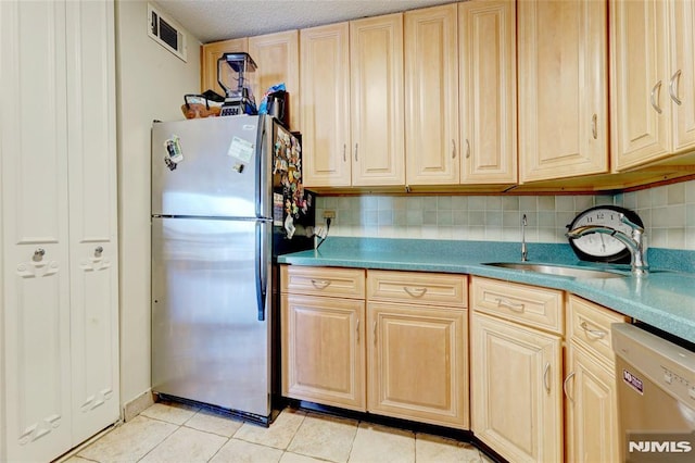 kitchen with sink, tasteful backsplash, light tile patterned floors, light brown cabinetry, and appliances with stainless steel finishes