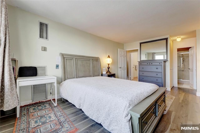 bedroom with connected bathroom and hardwood / wood-style flooring