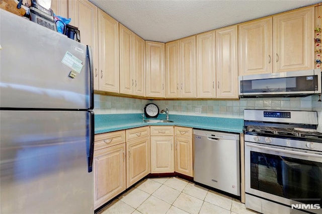 kitchen featuring sink, a textured ceiling, light brown cabinetry, light tile patterned flooring, and stainless steel appliances