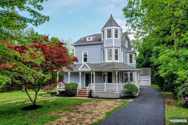 victorian-style house with a front yard, covered porch, an outdoor structure, and a garage