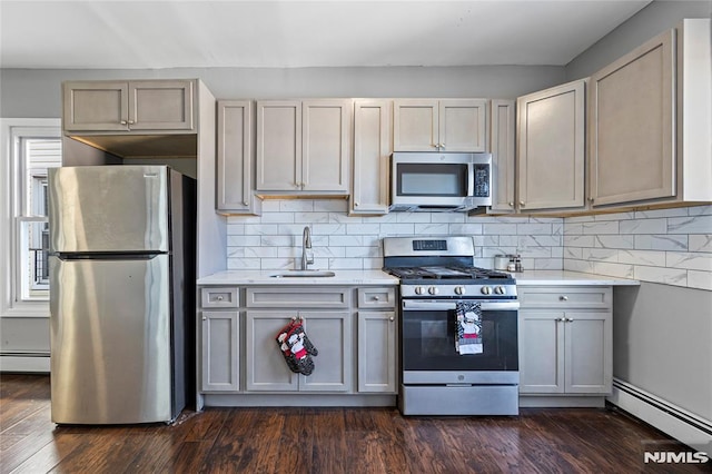 kitchen featuring dark hardwood / wood-style flooring, stainless steel appliances, a baseboard radiator, and sink