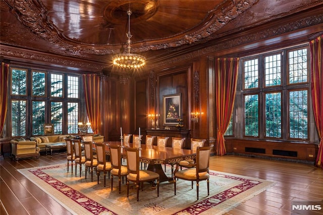 interior space with a high ceiling, hardwood / wood-style flooring, a chandelier, wooden walls, and ornamental molding