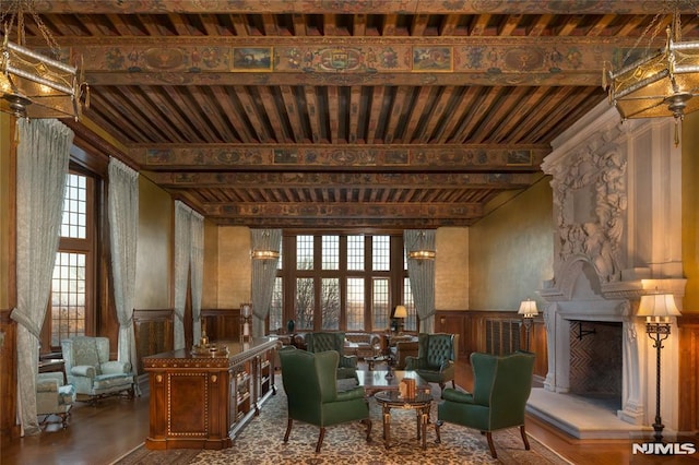 sitting room with beamed ceiling, a large fireplace, and decorative columns