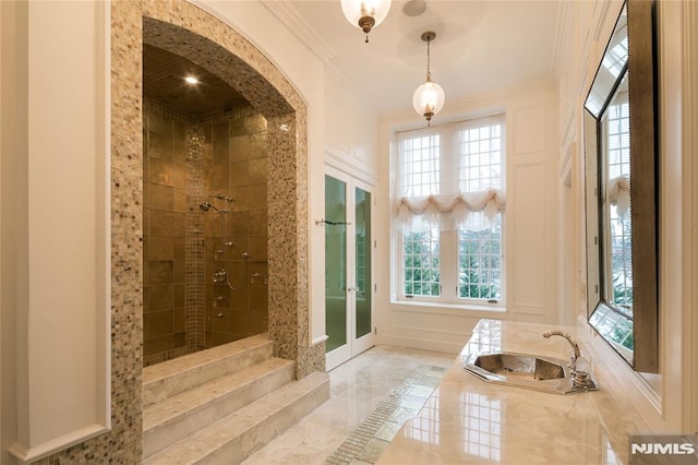 bathroom featuring tiled shower, sink, and crown molding