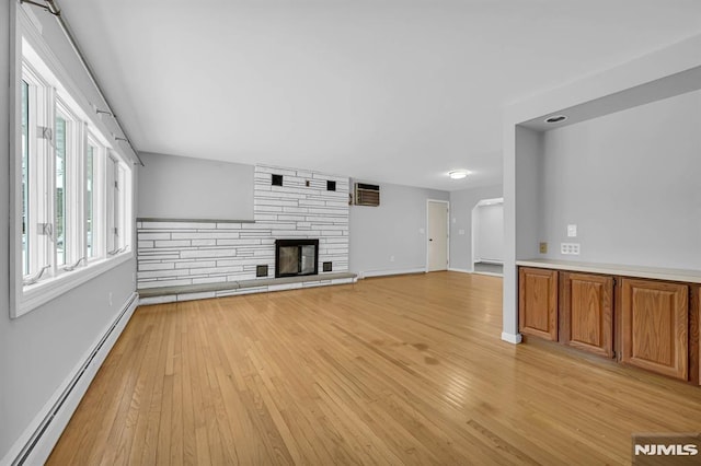 unfurnished living room with a fireplace, light hardwood / wood-style floors, and a baseboard heating unit