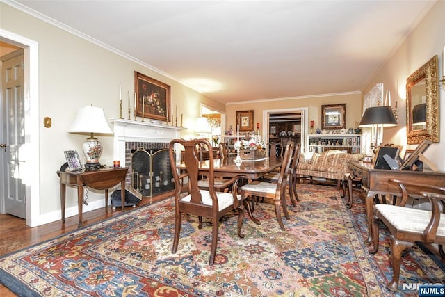 dining area with hardwood / wood-style floors, a brick fireplace, and crown molding