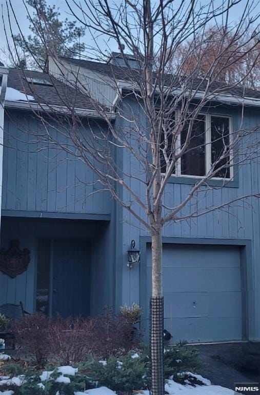 view of snowy exterior featuring a garage and driveway