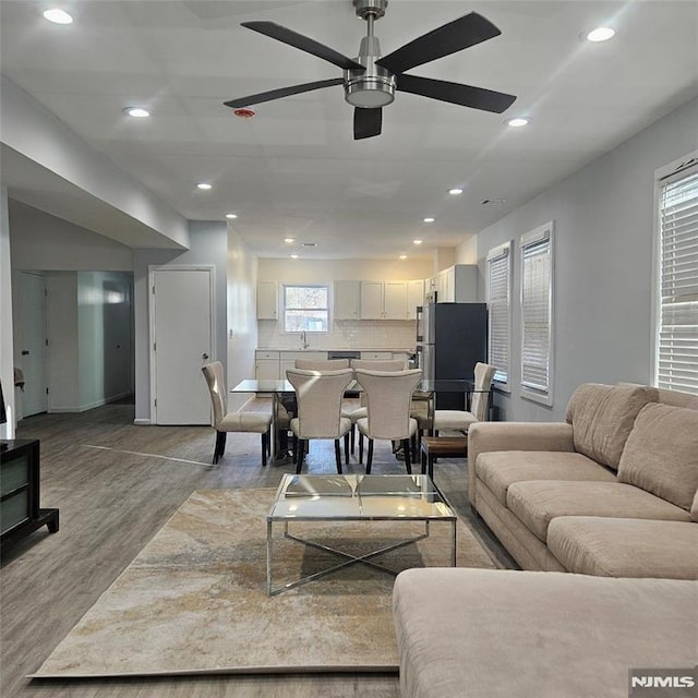 living room featuring ceiling fan, sink, and light hardwood / wood-style floors