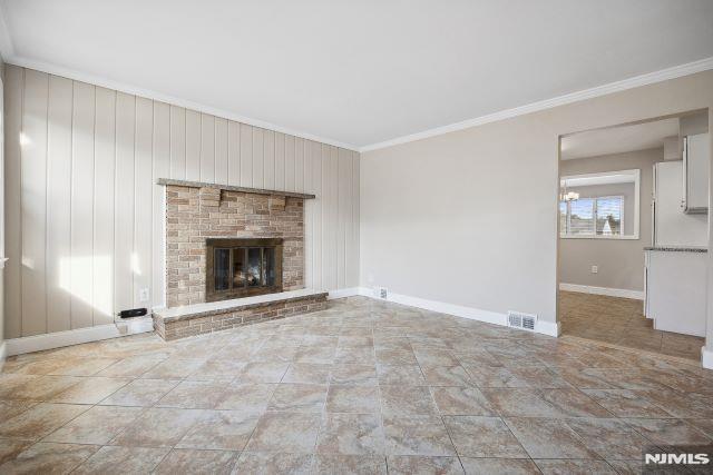 unfurnished living room with crown molding, a fireplace, and wooden walls