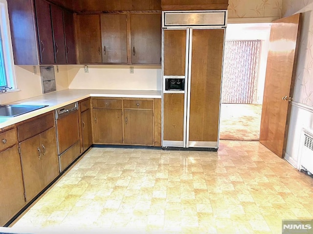 kitchen with radiator, paneled built in fridge, sink, and stainless steel dishwasher