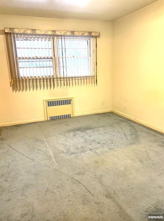 carpeted empty room featuring radiator heating unit