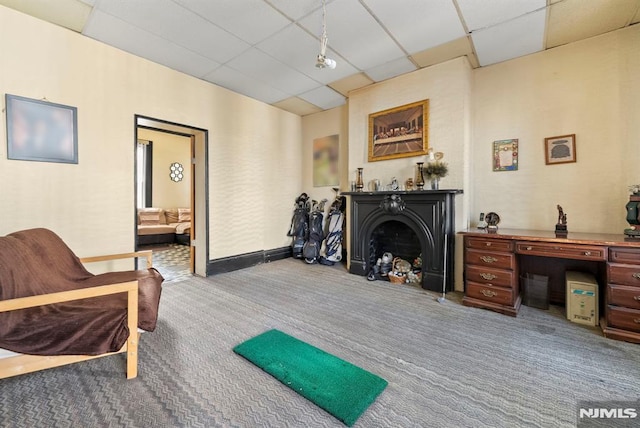 living area featuring light carpet, a drop ceiling, and a fireplace