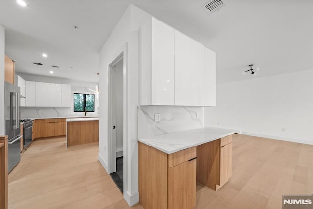 kitchen featuring backsplash, light stone countertops, white cabinets, and stainless steel appliances