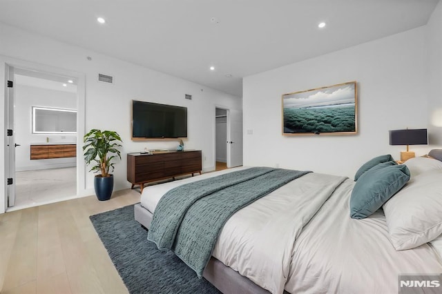 bedroom with ensuite bathroom and light wood-type flooring