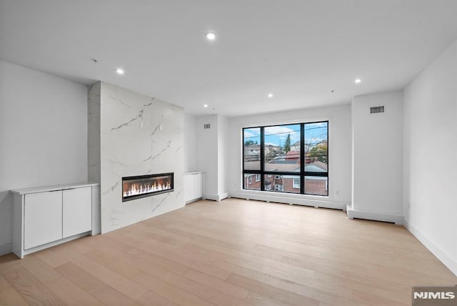 unfurnished living room featuring light hardwood / wood-style flooring and a high end fireplace