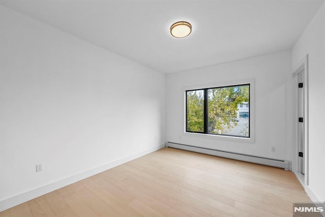 empty room with light wood-type flooring and a baseboard heating unit