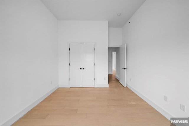 unfurnished bedroom with light wood-type flooring and a closet