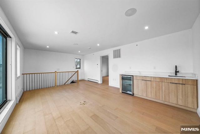 kitchen with wine cooler, sink, a baseboard radiator, and light wood-type flooring