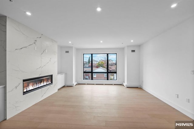 unfurnished living room featuring light hardwood / wood-style flooring and a high end fireplace