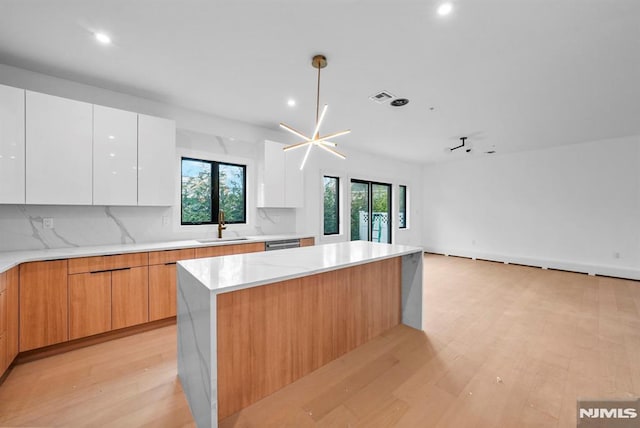 kitchen with white cabinets, backsplash, pendant lighting, and sink