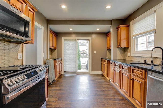 kitchen with sink, stainless steel appliances, a wealth of natural light, and dark stone countertops