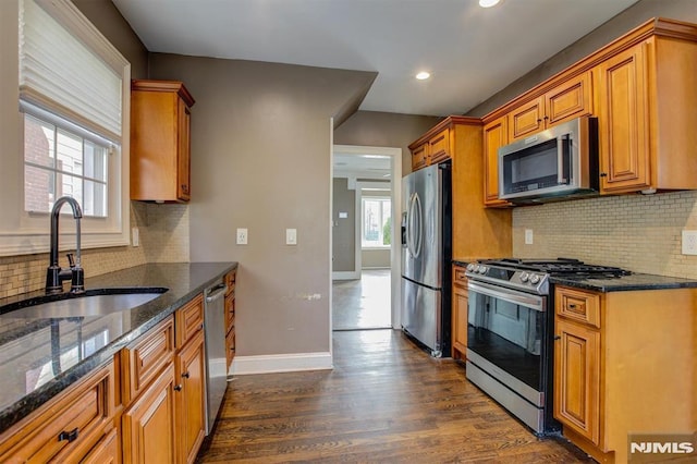 kitchen with dark hardwood / wood-style floors, sink, appliances with stainless steel finishes, and dark stone counters