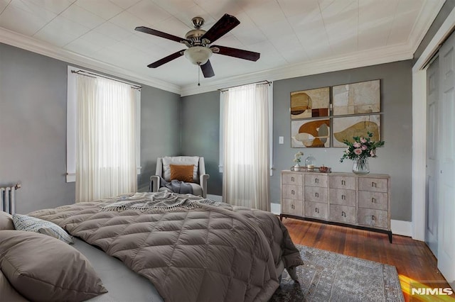 bedroom featuring ornamental molding, ceiling fan, radiator heating unit, dark hardwood / wood-style floors, and a closet