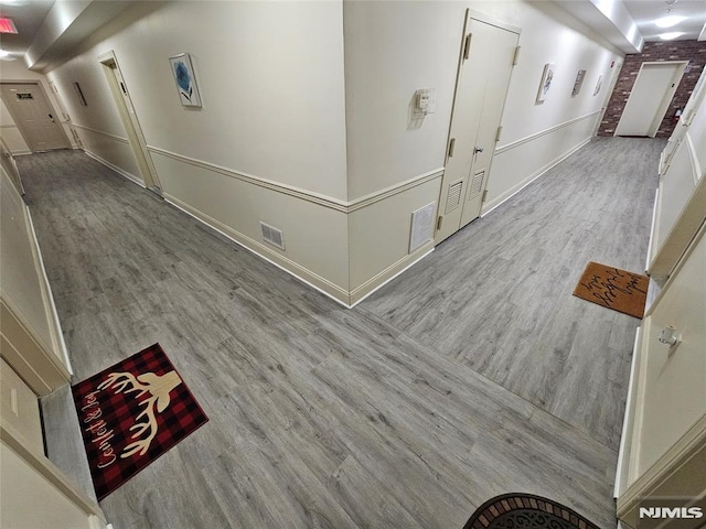 hallway featuring light hardwood / wood-style floors and brick wall