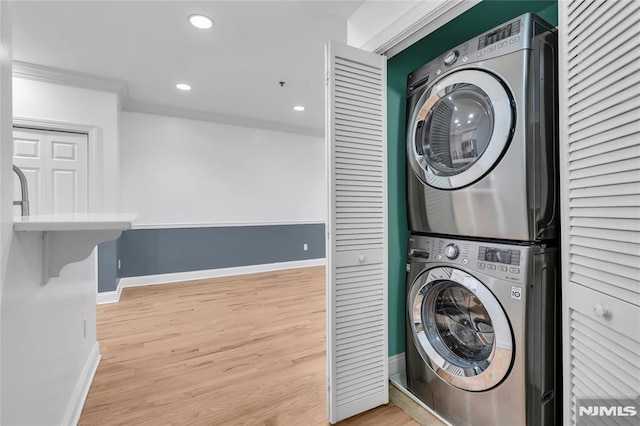 washroom with crown molding, stacked washer and dryer, and hardwood / wood-style floors