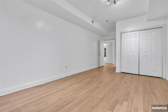 unfurnished bedroom with light hardwood / wood-style flooring and a closet