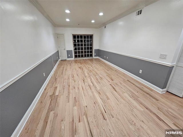 empty room featuring light wood-type flooring and ornamental molding