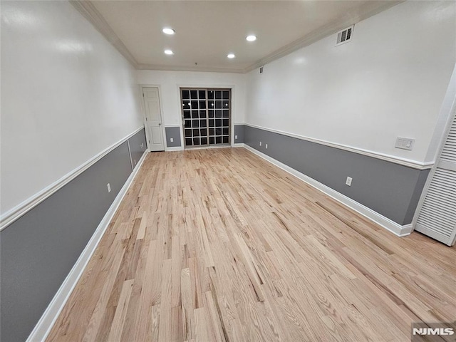 spare room with ornamental molding and light hardwood / wood-style flooring