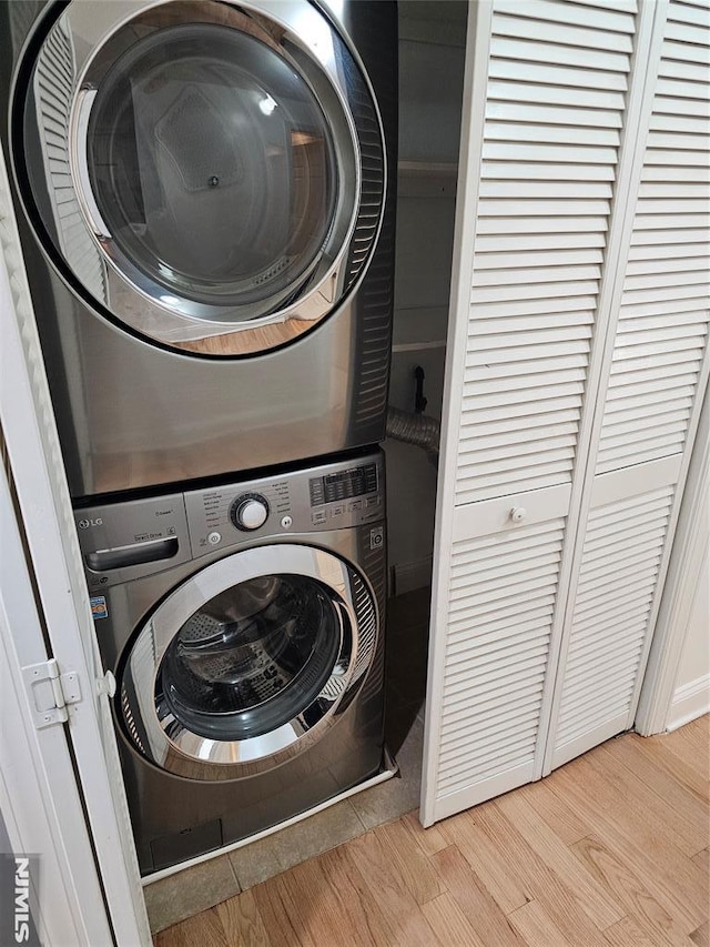 clothes washing area featuring stacked washer and dryer and light hardwood / wood-style flooring